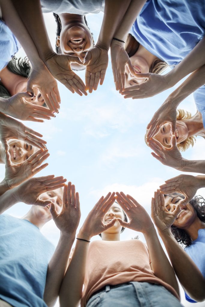 a group of people standing in a circle with their hands together.